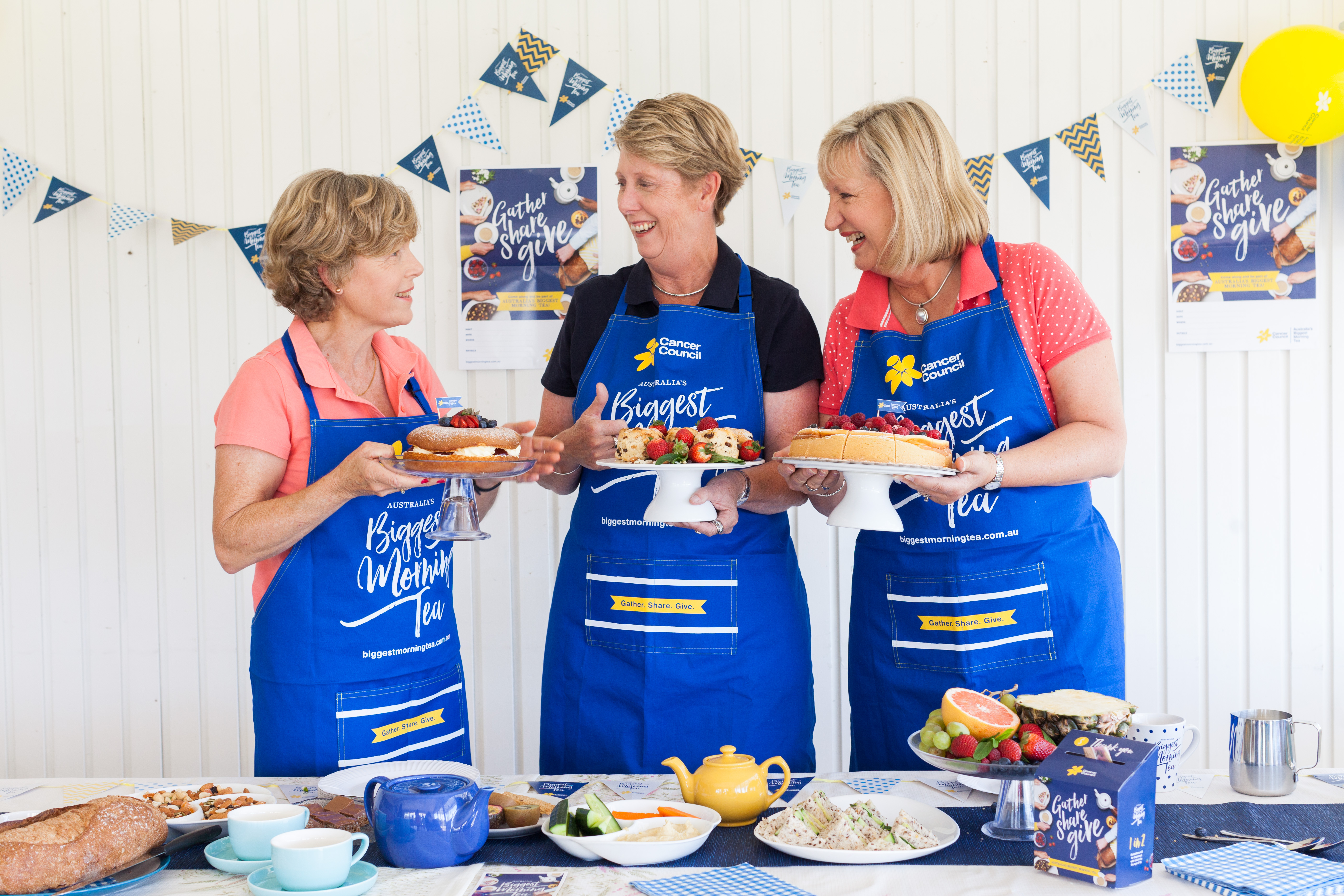 women holding cakes and scones and talking happily. three women hosting a morning tea.